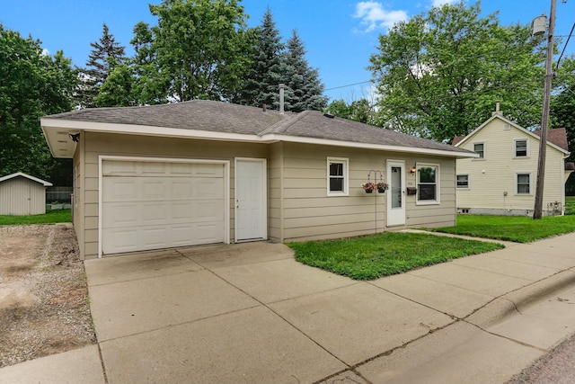 404 2nd St W, Jordan, MN 55352 - view of front of house with driveway, a garage, a front yard, roof with shingles, and a shed