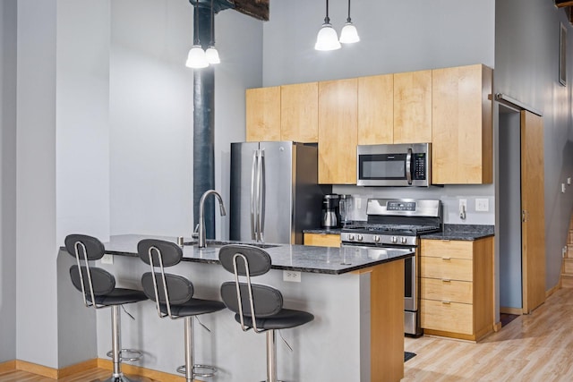 406 Wacouta St Unit 207, Saint Paul, MN 55101 - kitchen featuring appliances with stainless steel finishes, a breakfast bar, dark stone countertops, hanging light fixtures, and a towering ceiling