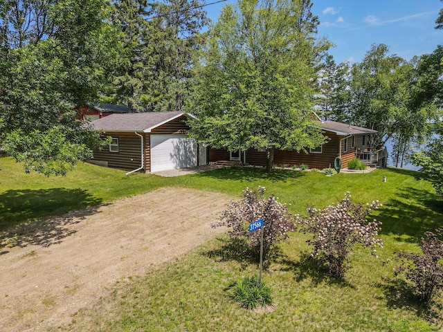 37566 Tulaby Lake Dr, Waubun, MN 56589 - view of front facade featuring dirt driveway, a front yard, log veneer siding, and a garage