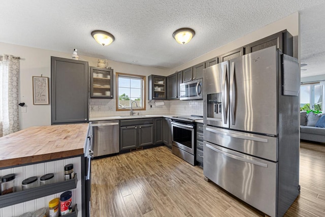 2115 Turpin St, Saint Peter, MN 56082 - kitchen featuring stainless steel appliances, butcher block counters, decorative backsplash, light wood-style floors, and glass insert cabinets