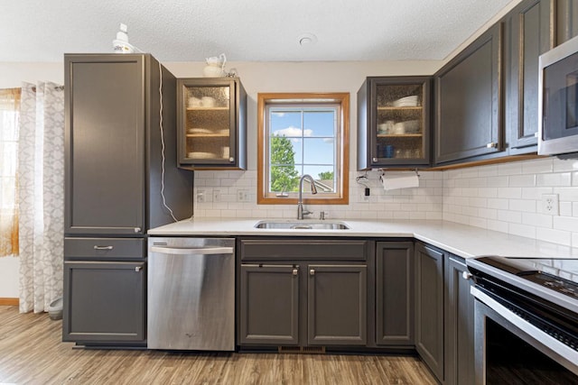 2115 Turpin St, Saint Peter, MN 56082 - kitchen featuring stainless steel appliances, light countertops, light wood finished floors, tasteful backsplash, and a textured ceiling