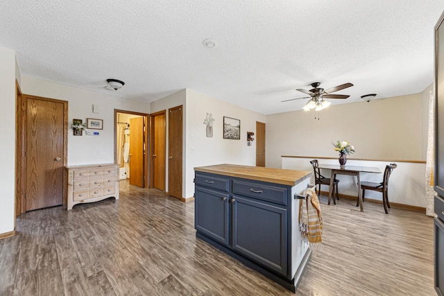 2115 Turpin St, Saint Peter, MN 56082 - kitchen with butcher block countertops, blue cabinets, a textured ceiling, wood finished floors, and ceiling fan