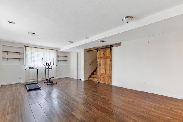2115 Turpin St, Saint Peter, MN 56082 - exercise area with wood finished floors, a barn door, and a textured ceiling