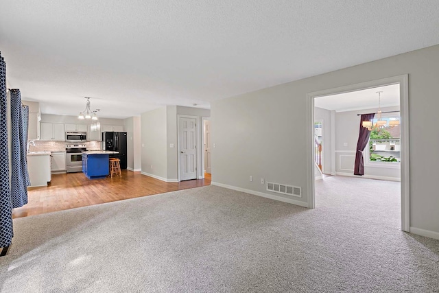 5245 Dufferin Dr, Savage, MN 55378 - unfurnished living room featuring a chandelier, light colored carpet, and a textured ceiling