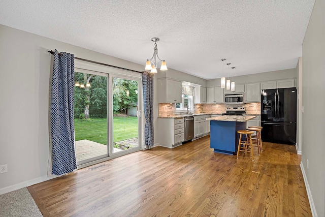 5245 Dufferin Dr, Savage, MN 55378 - kitchen featuring stainless steel appliances, a chandelier, decorative backsplash, a kitchen breakfast bar, and wood finished floors
