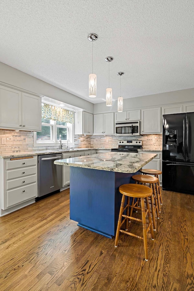 5245 Dufferin Dr, Savage, MN 55378 - kitchen featuring stainless steel appliances, a textured ceiling, a center island, dark wood-type flooring, and tasteful backsplash