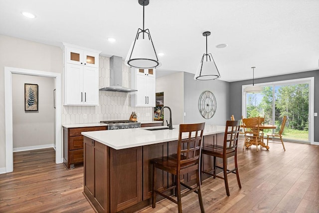 4335 Spring View Dr, Moose Lake, MN 55767 - kitchen with wall chimney exhaust hood, wood finished floors, backsplash, an island with sink, and light countertops