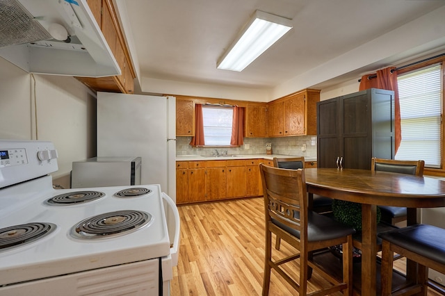 5041 Upton Ave N, Minneapolis, MN 55430 - kitchen featuring white appliances, exhaust hood, light countertops, light wood-style floors, and brown cabinetry