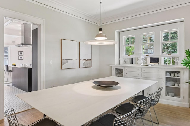 4626 Dupont Ave S, Minneapolis, MN 55419 - kitchen featuring wall chimney range hood, light wood-style floors, white cabinets, ornamental molding, and pendant lighting
