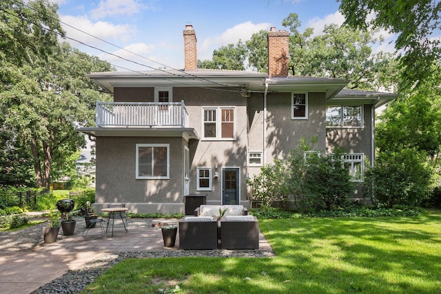 4626 Dupont Ave S, Minneapolis, MN 55419 - rear view of house featuring a balcony, stucco siding, a patio, a lawn, and a chimney