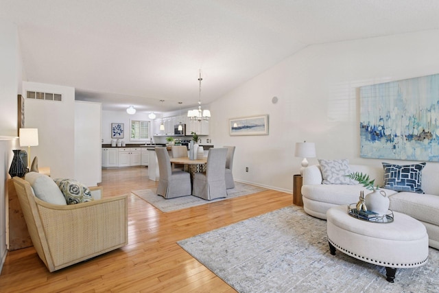 913 Carriage Ln, Chaska, MN 55318 - living room with vaulted ceiling, a chandelier, and light wood finished floors