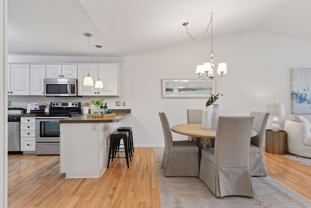 913 Carriage Ln, Chaska, MN 55318 - kitchen featuring appliances with stainless steel finishes, white cabinets, lofted ceiling, dark countertops, and a kitchen breakfast bar