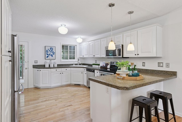 913 Carriage Ln, Chaska, MN 55318 - kitchen with stainless steel appliances, a peninsula, dark countertops, white cabinets, and a textured ceiling