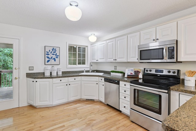 913 Carriage Ln, Chaska, MN 55318 - kitchen featuring appliances with stainless steel finishes, light wood finished floors, white cabinetry, a textured ceiling, and dark countertops