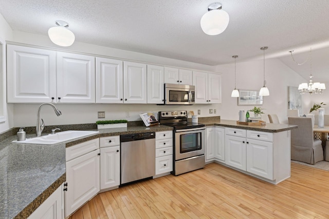 913 Carriage Ln, Chaska, MN 55318 - kitchen featuring stainless steel appliances, a peninsula, white cabinets, light wood-style flooring, and dark countertops