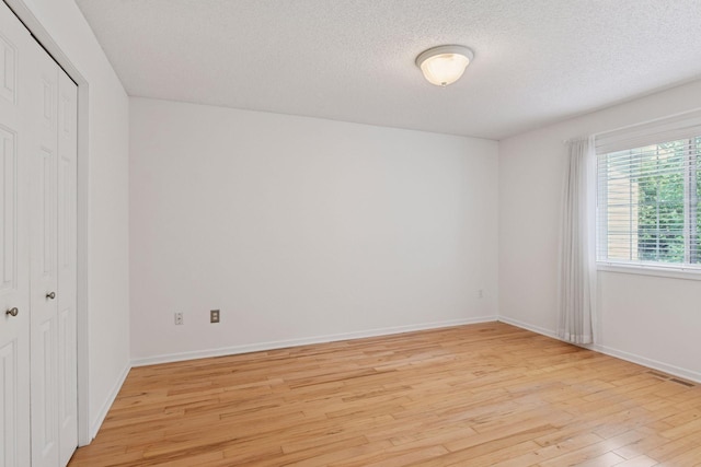 913 Carriage Ln, Chaska, MN 55318 - unfurnished bedroom with light wood finished floors, a closet, and a textured ceiling