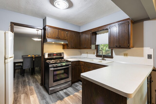 10048 Upton Rd, Bloomington, MN 55431 - kitchen featuring stainless steel range with gas stovetop, under cabinet range hood, freestanding refrigerator, light wood-type flooring, and dark brown cabinetry