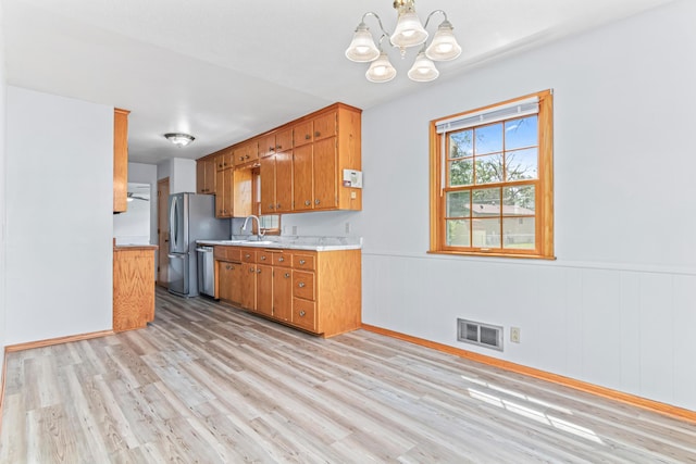 1920 108th Ln NW, Coon Rapids, MN 55433 - kitchen featuring light countertops, stainless steel appliances, light wood-style floors, a chandelier, and a wainscoted wall