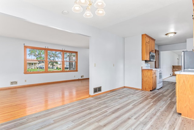 1920 108th Ln NW, Coon Rapids, MN 55433 - kitchen with white range, stainless steel microwave, freestanding refrigerator, light wood finished floors, and a chandelier