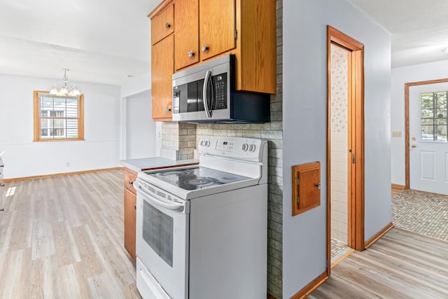 1920 108th Ln NW, Coon Rapids, MN 55433 - kitchen with white electric range, stainless steel microwave, light wood-type flooring, a chandelier, and brown cabinetry