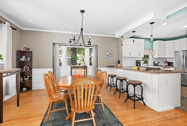 4223 Mcculloch St, Duluth, MN 55804 - dining space featuring light wood-style floors, a wainscoted wall, ornamental molding, and a chandelier