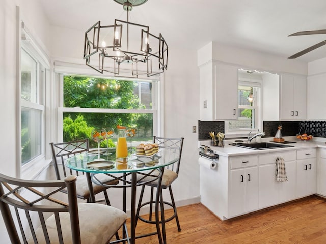 910 62nd St, Minneapolis, MN 55419 - kitchen with decorative backsplash, light wood-style floors, white cabinets, light countertops, and a chandelier
