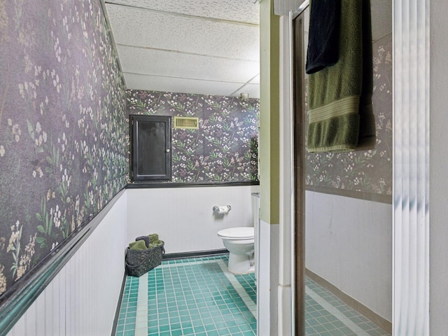 910 62nd St, Minneapolis, MN 55419 - bathroom featuring wallpapered walls, a paneled ceiling, tile patterned flooring, and wainscoting