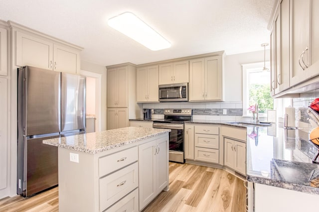 141 145th Ln NE, Ham Lake, MN 55304 - kitchen with stainless steel appliances, light wood-style floors, dark stone counters, backsplash, and a kitchen island
