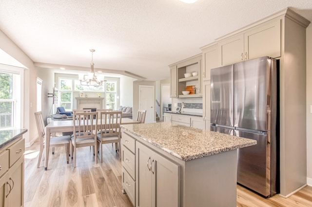 141 145th Ln NE, Ham Lake, MN 55304 - kitchen with freestanding refrigerator, open shelves, light wood-type flooring, a kitchen island, and light stone countertops