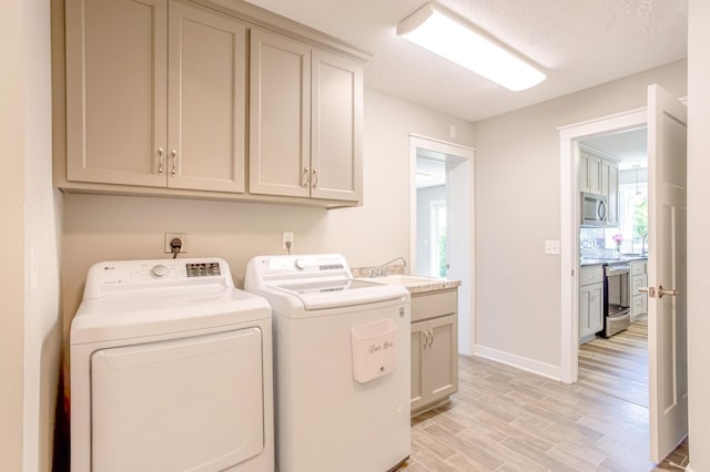 141 145th Ln NE, Ham Lake, MN 55304 - laundry area with washer and dryer, cabinet space, light wood-style flooring, and a textured ceiling