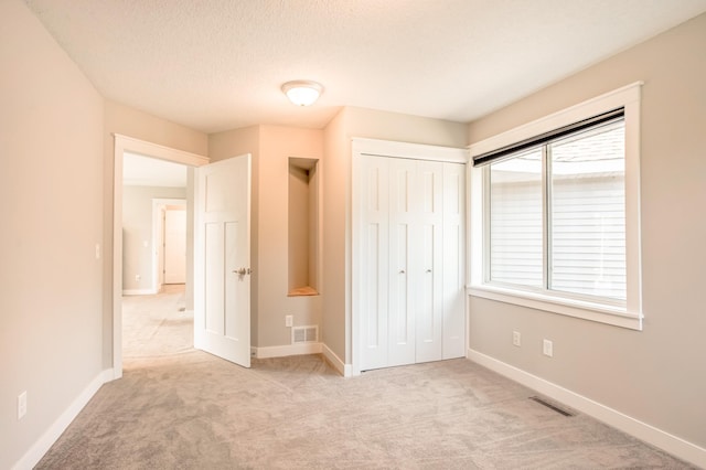 141 145th Ln NE, Ham Lake, MN 55304 - unfurnished bedroom featuring light carpet, a closet, and a textured ceiling