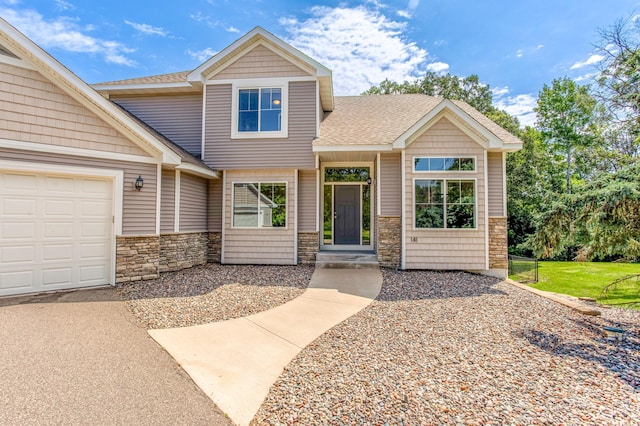 141 145th Ln NE, Ham Lake, MN 55304 - view of front of property featuring stone siding, a shingled roof, an attached garage, and asphalt driveway