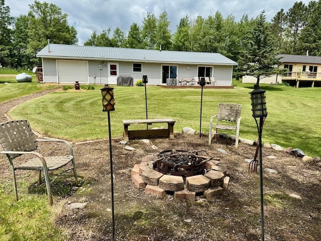 63714 Hannu Ln, Pine Lake Twp, MN 55735 - exterior space featuring an outdoor fire pit, a metal roof, a front lawn, and an attached garage