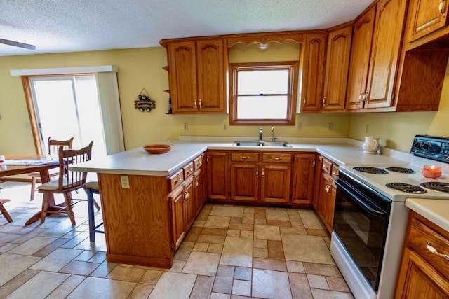 63714 Hannu Ln, Pine Lake Twp, MN 55735 - kitchen with white range with electric cooktop, a peninsula, brown cabinets, plenty of natural light, and a textured ceiling