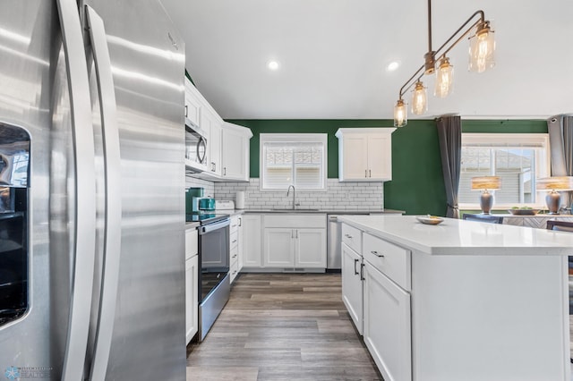 1009 Highland Ln W, West Fargo, ND 58078 - kitchen featuring appliances with stainless steel finishes, backsplash, white cabinetry, dark wood-style floors, and a kitchen island