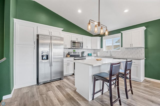 1009 Highland Ln W, West Fargo, ND 58078 - kitchen featuring stainless steel appliances, decorative backsplash, light wood finished floors, white cabinetry, and lofted ceiling