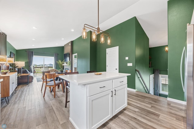 1009 Highland Ln W, West Fargo, ND 58078 - kitchen with white cabinets, light wood finished floors, light countertops, a center island, and freestanding refrigerator