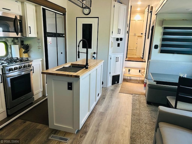 23488 Waskawood Rd # 110, Long Beach, MN 56334 - kitchen featuring butcher block countertops, appliances with stainless steel finishes, dark wood-style floors, and white cabinets