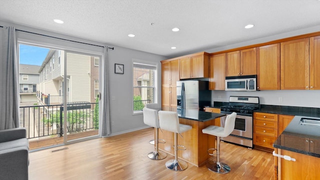 11333 Stratton Ave, Eden Prairie, MN 55344 - kitchen with appliances with stainless steel finishes, light wood-style floors, a breakfast bar area, recessed lighting, and a kitchen island