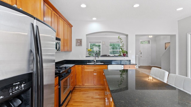 11333 Stratton Ave, Eden Prairie, MN 55344 - kitchen with stainless steel appliances, brown cabinets, dark stone counters, recessed lighting, and arched walkways