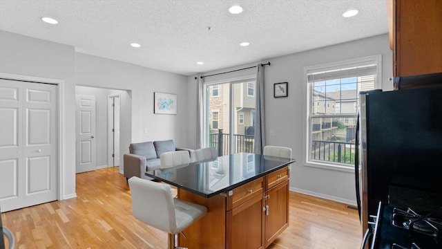 11333 Stratton Ave, Eden Prairie, MN 55344 - kitchen with brown cabinetry, a breakfast bar, light wood-style floors, a textured ceiling, and freestanding refrigerator