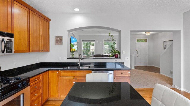 11333 Stratton Ave, Eden Prairie, MN 55344 - kitchen with stainless steel appliances, open floor plan, brown cabinets, dark stone counters, and a textured ceiling
