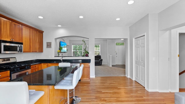 11333 Stratton Ave, Eden Prairie, MN 55344 - kitchen with stainless steel appliances, a kitchen island, light wood-type flooring, recessed lighting, and a breakfast bar area