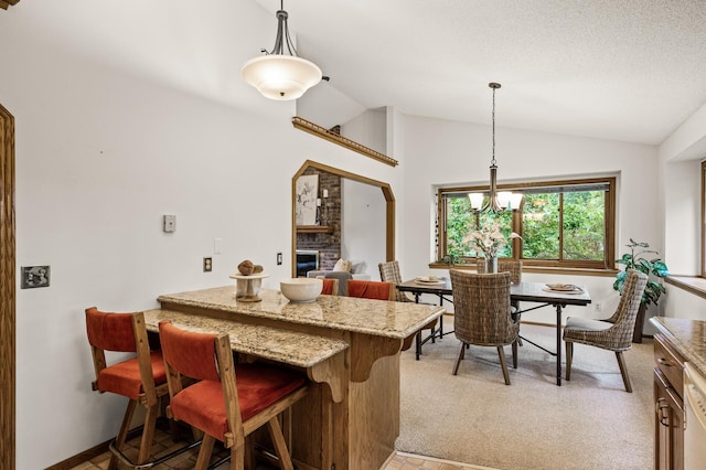 1306 Wynridge Dr, Arden Hills, MN 55112 - kitchen featuring lofted ceiling, a fireplace, a kitchen breakfast bar, light stone countertops, and hanging light fixtures