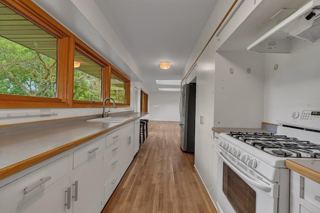 5848 16th Ave SE, Haven Twp, MN 56304 - kitchen featuring white gas range, ventilation hood, freestanding refrigerator, white cabinets, and light wood finished floors