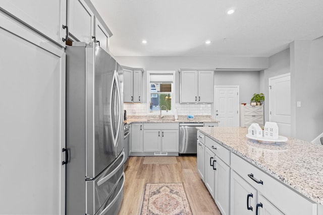 14811 Willemite St NW, Ramsey, MN 55303 - kitchen with appliances with stainless steel finishes, backsplash, light wood-style floors, light stone countertops, and recessed lighting