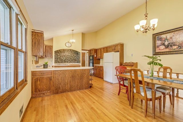 5577 Alameda St, Shoreview, MN 55126 - kitchen featuring a chandelier, brown cabinetry, a peninsula, high vaulted ceiling, and light wood-style floors