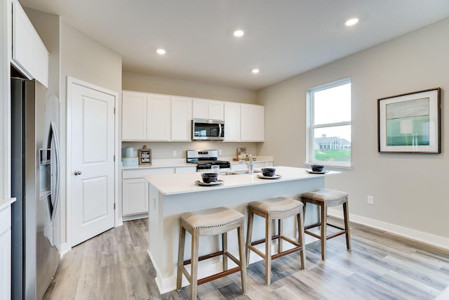 12577 Marshview Dr, Rogers, MN 55374 - kitchen with stainless steel appliances, light wood-style flooring, a kitchen breakfast bar, white cabinetry, and light countertops