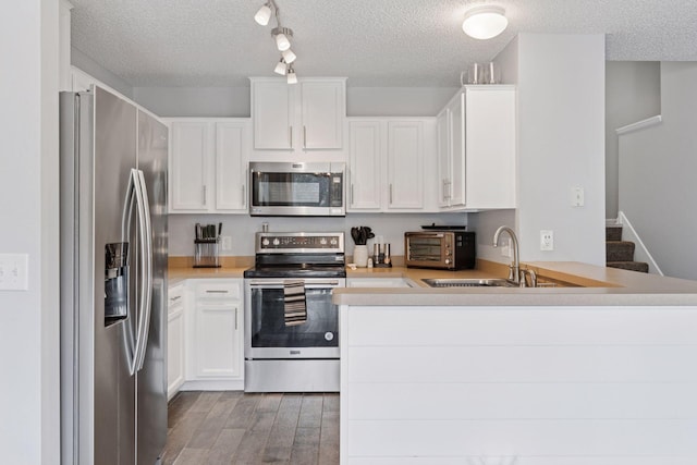 6845 Christian Curv, Woodbury, MN 55125 - kitchen featuring stainless steel appliances, a textured ceiling, light wood finished floors, a peninsula, and light countertops