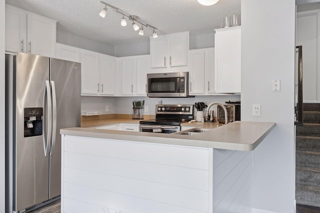6845 Christian Curv, Woodbury, MN 55125 - kitchen with stainless steel appliances, a textured ceiling, a peninsula, light countertops, and white cabinetry